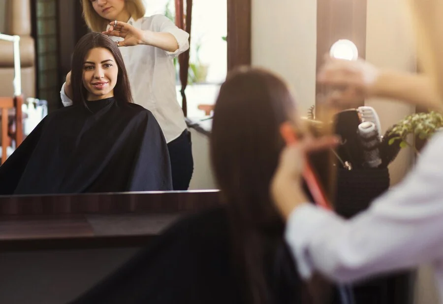 woman admiring her new hairstyle in the mirror at Chapter Two Hair Studio.